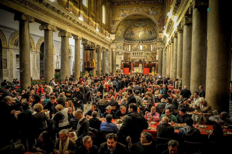 Tässäkö yksi tyhjenevien kirkkojen tulevaisuuden visio: katolisen maallikkoliikkeen Sant'Egidio -yhteisön vapaaehtoisten säännöllisesti järjestämä asunnottomien ja köyhien yhteinen ateria Roomassa Santa Maria in Trastevere basilikan kirkkosalissa.